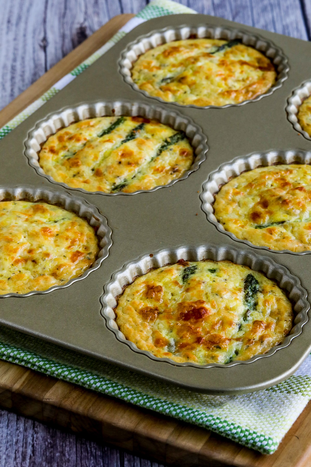 Asparagus Tarts in tart pan on cutting board.