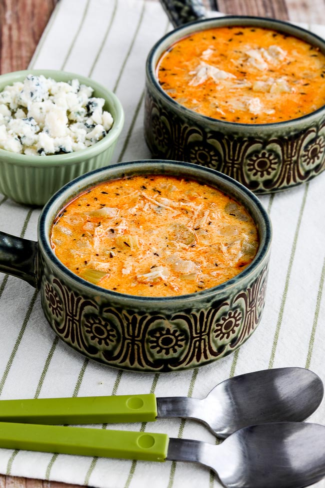 two bowls of buffalo chicken soup with crumbled blue cheese on the side