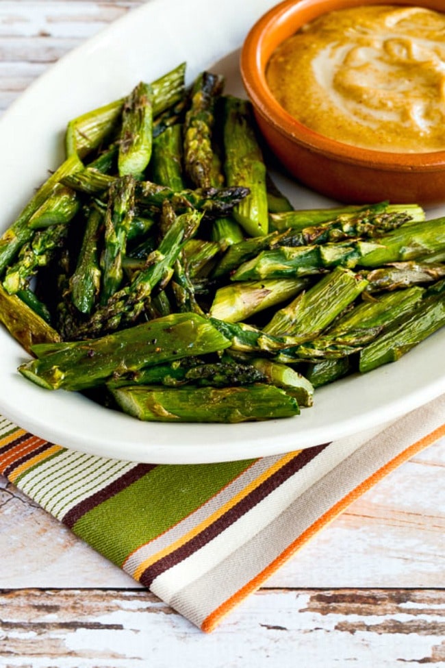 Asparagus with Tahini-Peanut Dipping Sauce shown on serving plate with napkin in background