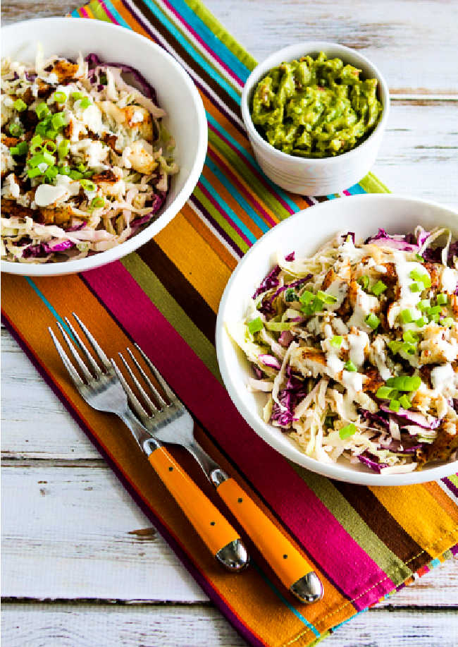 Fish taco cabbage bowl with fork and guacamole on napkin