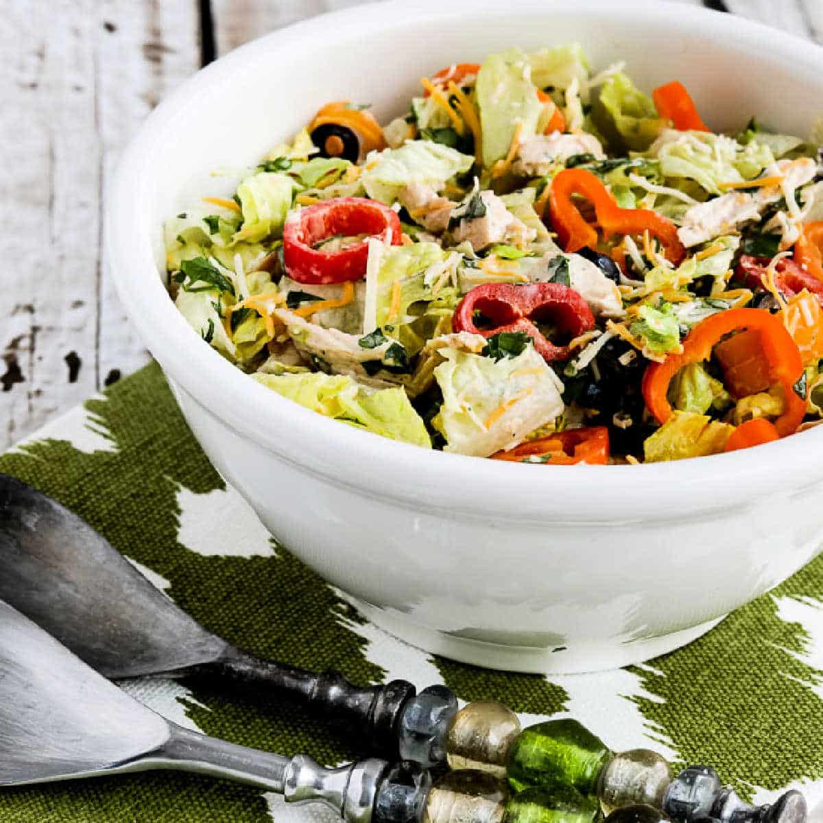Square image of Southwest Chicken Salad shown in serving bowl with large spoons.