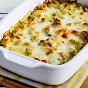 Square image of Chicken and Asparagus Bake with Creamy Curry Sauce in baking dish on cutting board.
