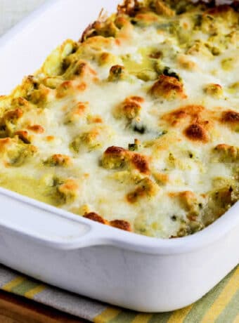 Square image of Chicken and Asparagus Bake with Creamy Curry Sauce in baking dish on cutting board.