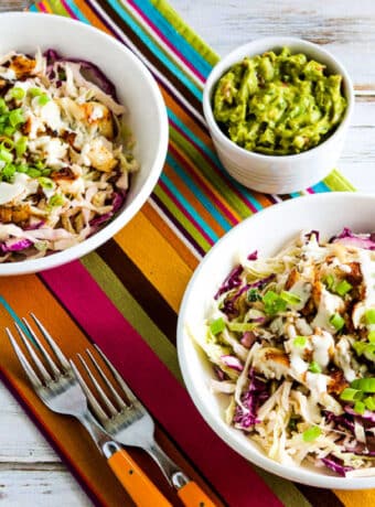square image of Fish Taco Cabbage Bowls shown on napkins with forks and guacamole