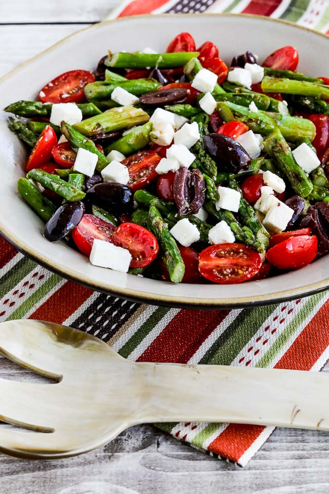 Asparagus Salad with Cherry Tomatoes, Kalamata Olives, and Feta on large serving dish with oversized serving spoon