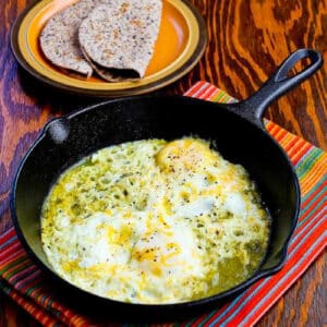 Square image of Fifteen Minute Salsa Verde Eggs with eggs in skillet and low-carb tortillas in back.
