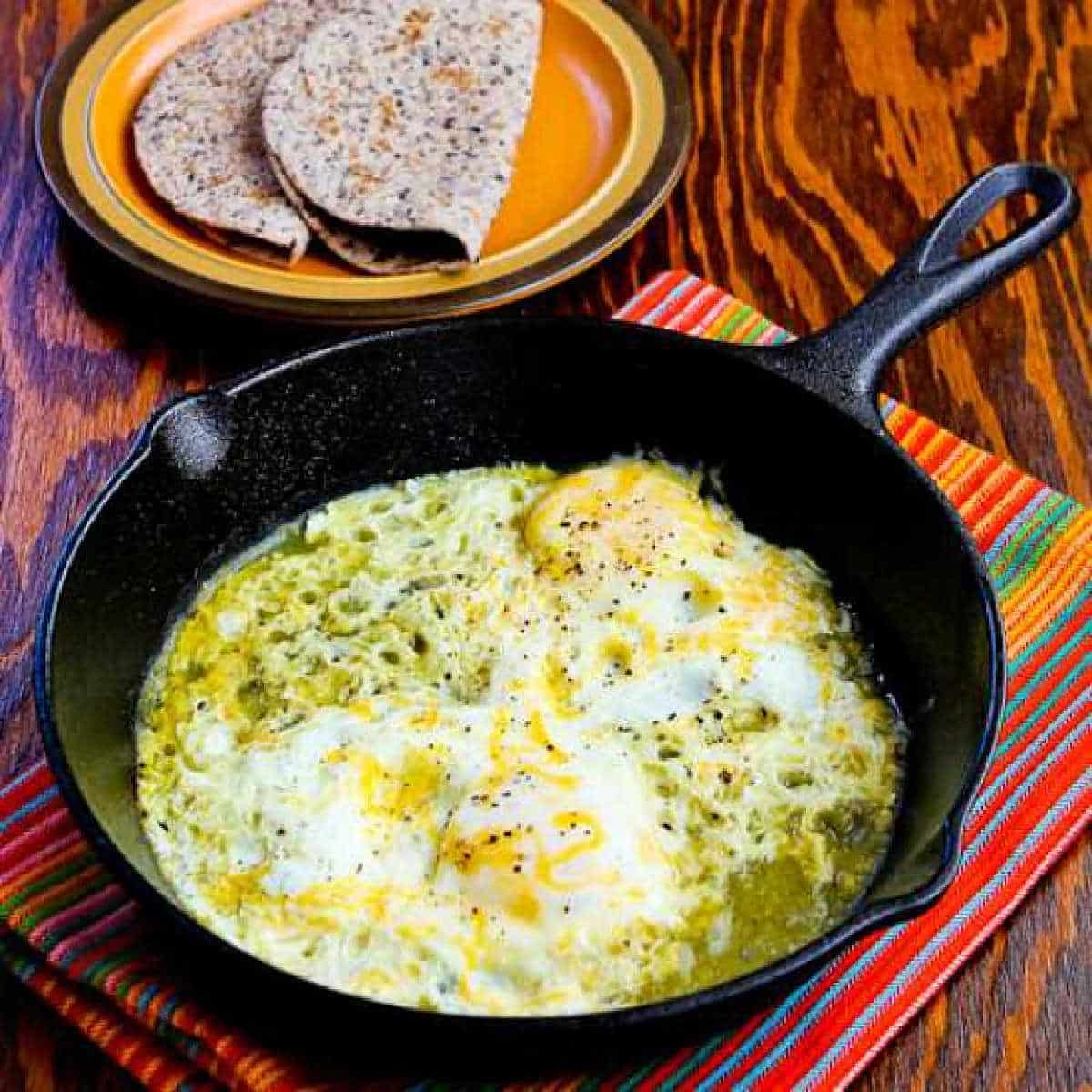 Square image of Fifteen Minute Salsa Verde Eggs with eggs in skillet and low-carb tortillas in back.