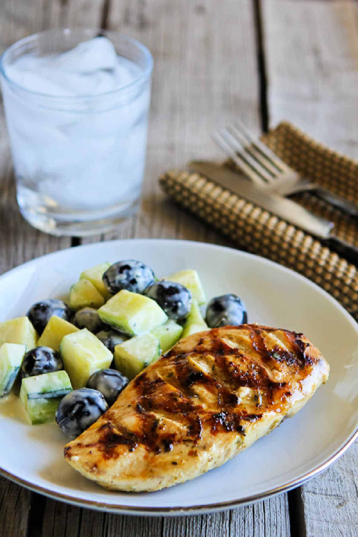 Grilled chicken with lemon and capers as shown in the serving dish with cucumber and olive salad