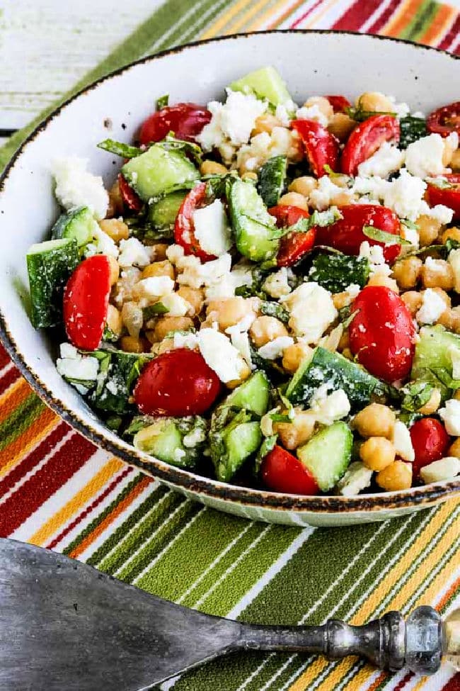 Tomato Cucumber Chickpea Salad shown in salad bowl with serving fork.