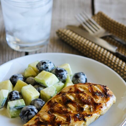 Grilled Chicken with Lemon, Capers, and Oregano on serving plate, with water glass, silverware, and napkin