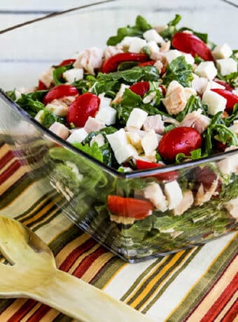 Arugula Chicken Salad in glass serving bowl with fork.