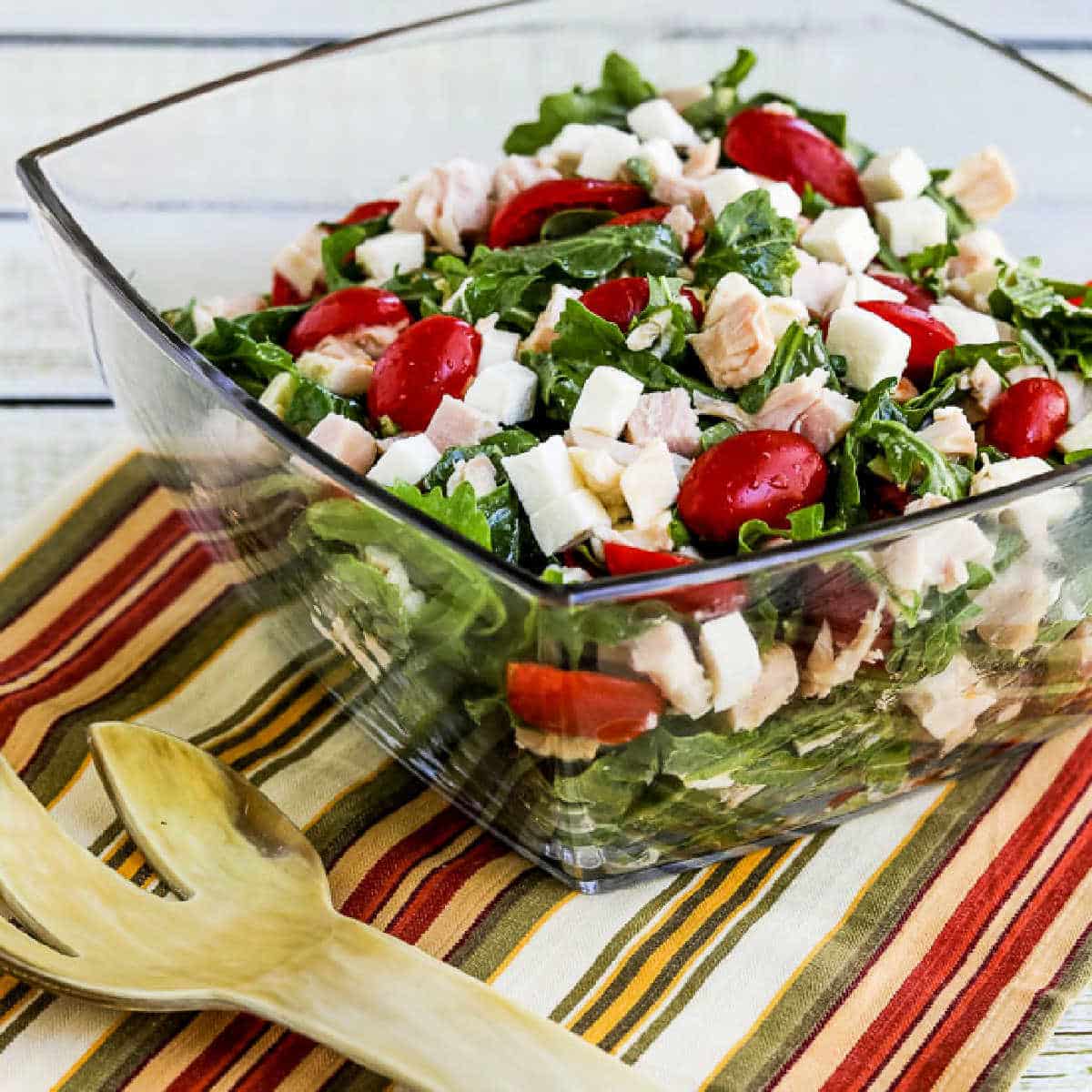 Arugula Chicken Salad in glass serving bowl with fork.