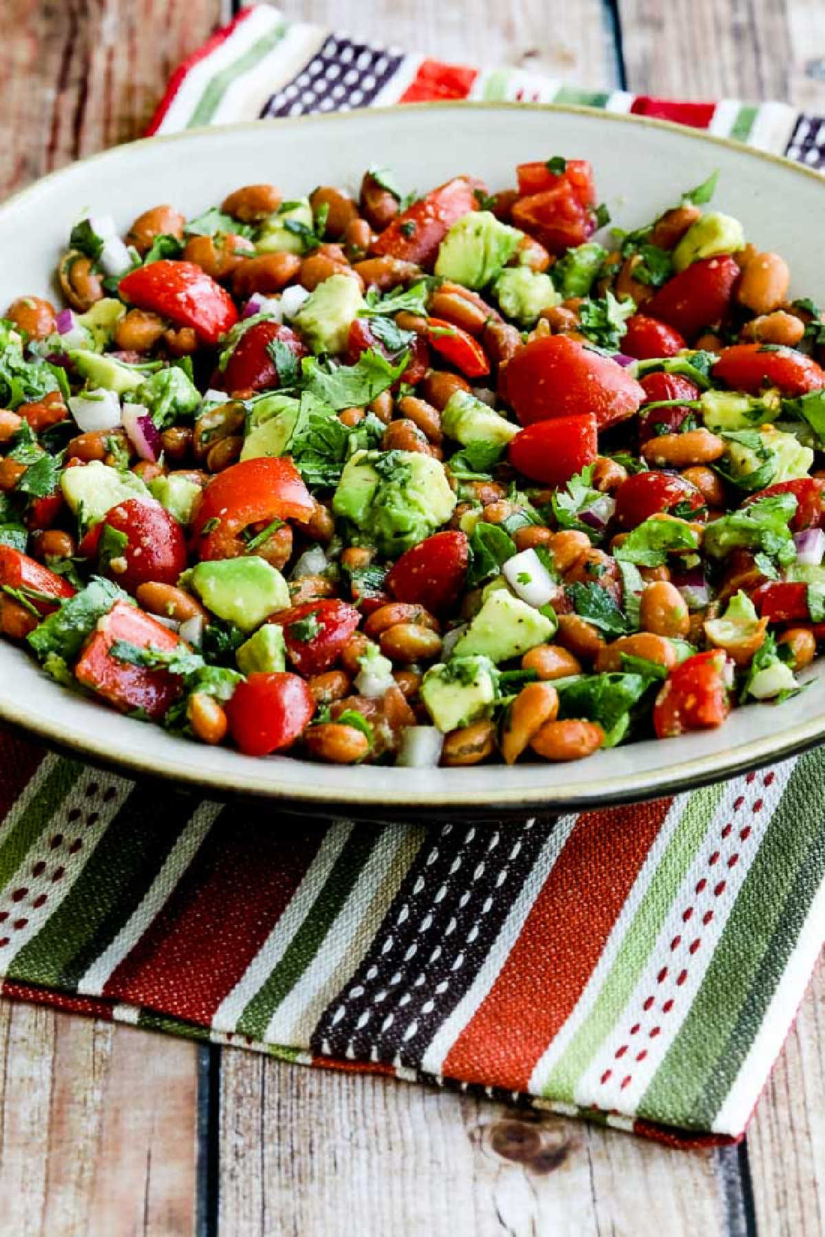 Pinto Bean Salad with Avocado and Tomatoes in serving bowl on striped napkin