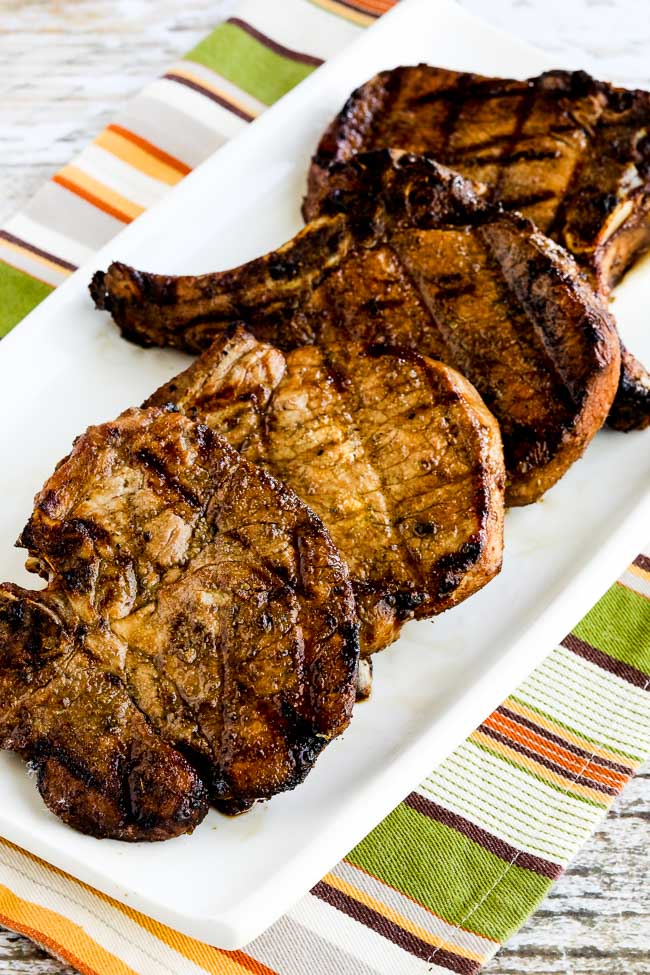 Marinated Pork Chops with Soy Sauce, Cumin, Lime, and Oregano show on serving plate on striped napkin