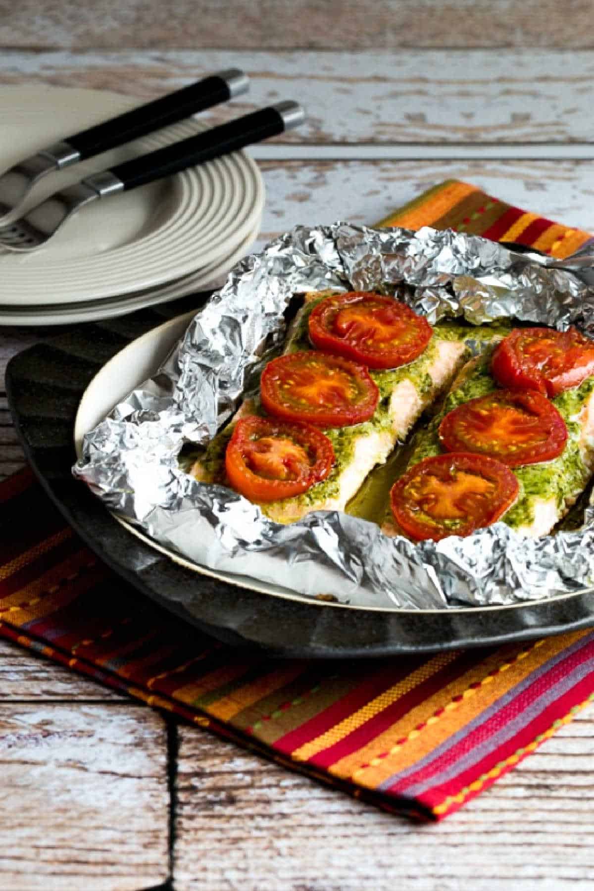 Baked Salmon with Pesto and Tomatoes shown in foil on serving plate