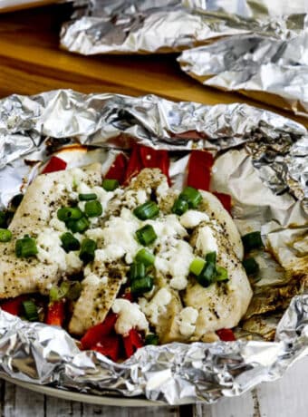 Greek Chicken Foil Packets with one packet open and wrapped ones in back.
