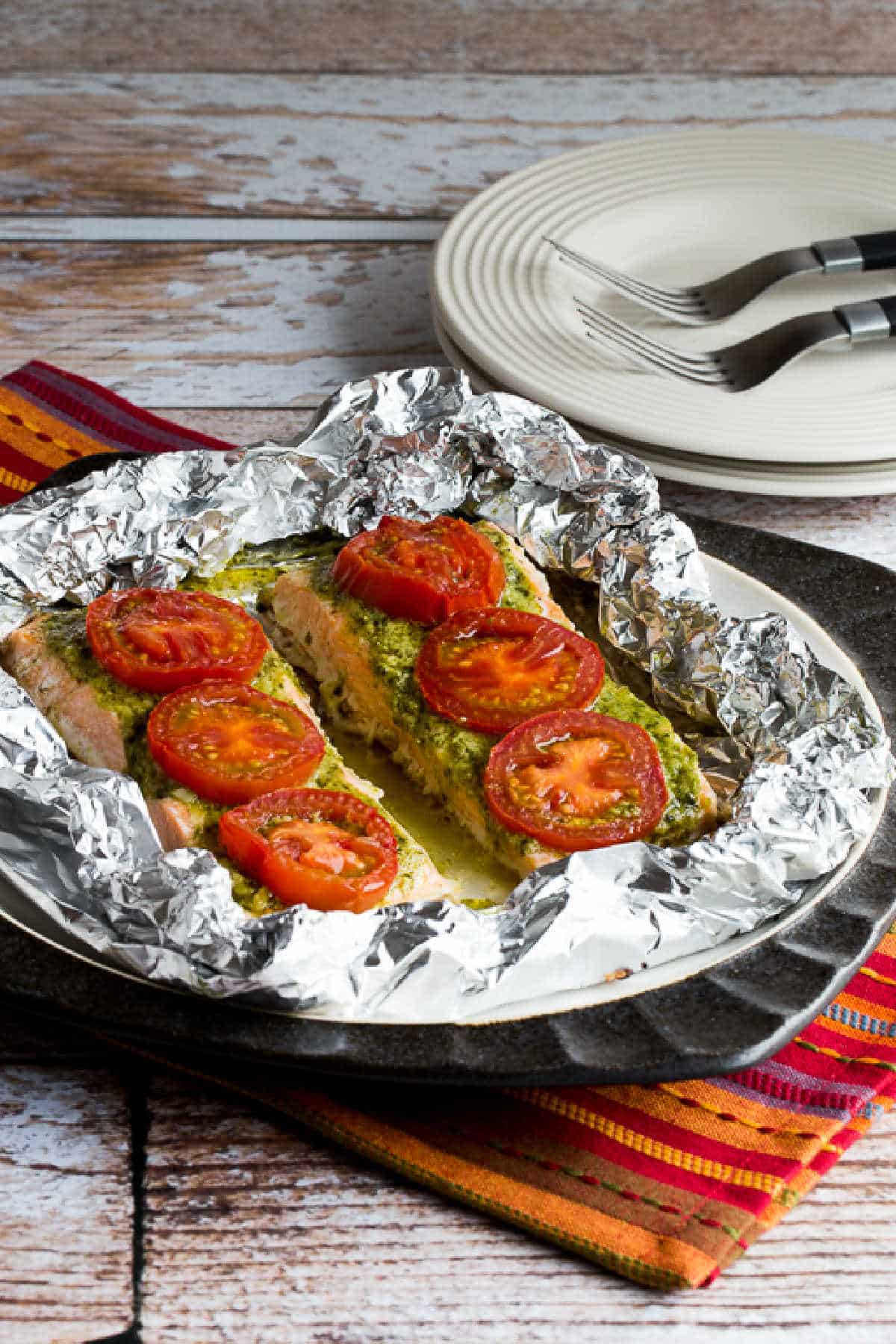 Baked Salmon with Pesto and Tomatoes close-up shot of salmon in foil on serving plate