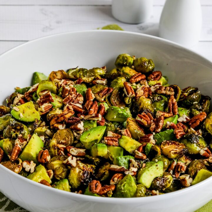 Roasted Brussels Sprouts with Avocados and Pecans shown in serving bowl on green-white napkin
