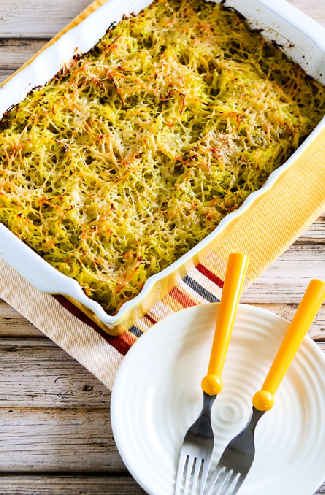 Twice-Baked Spaghetti Squash with Pesto in baking dish with plates and fork below