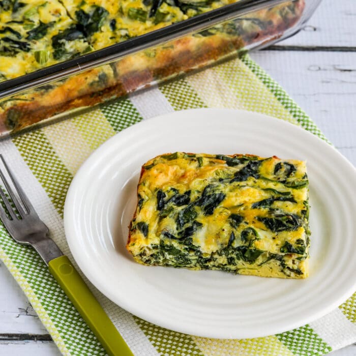 Image of spinach and mozzarella egg mini square with one slice on plate and egg baked in casserole in the background