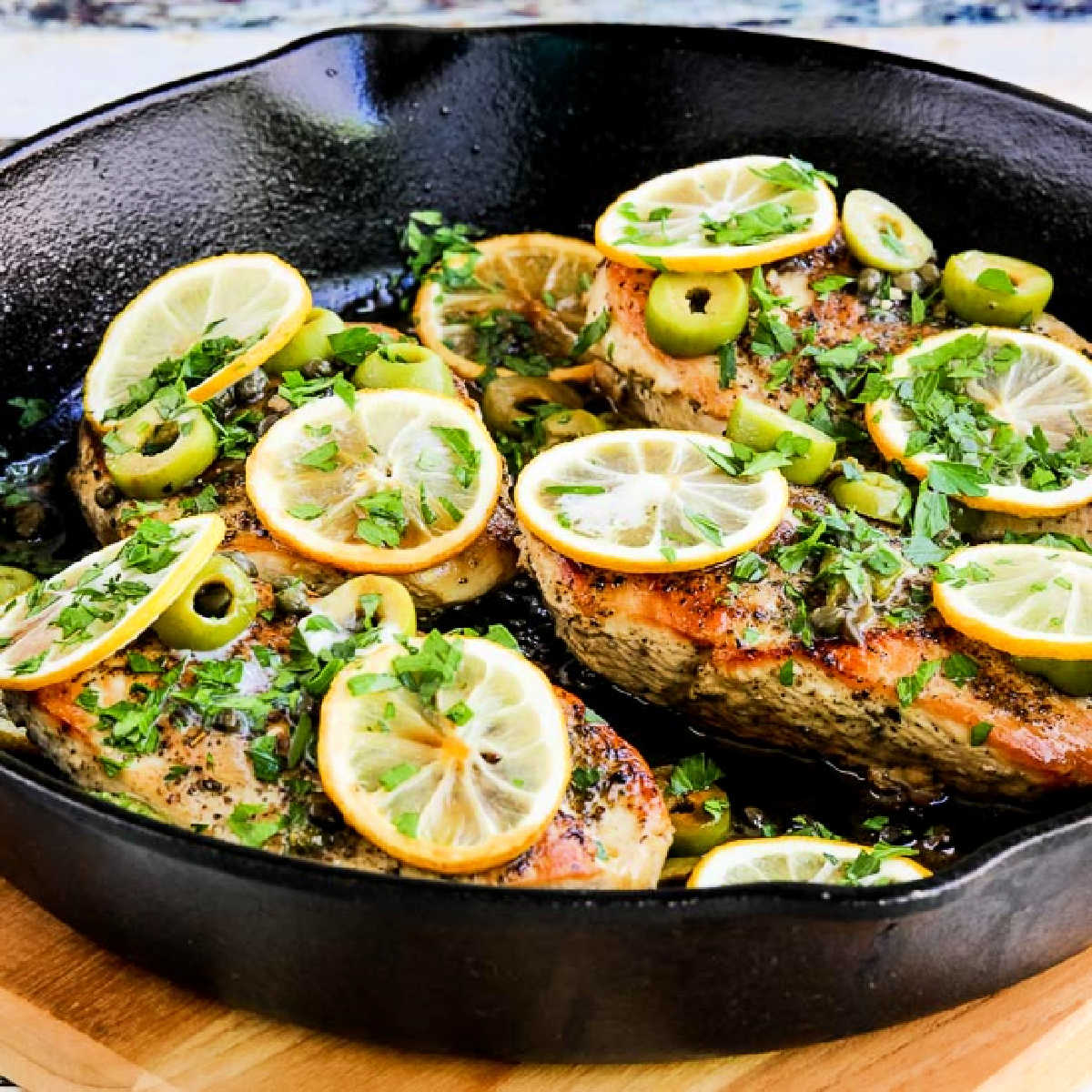 Chicken with Lemons, Green Olives, and Capers shown in cast-iron skillet