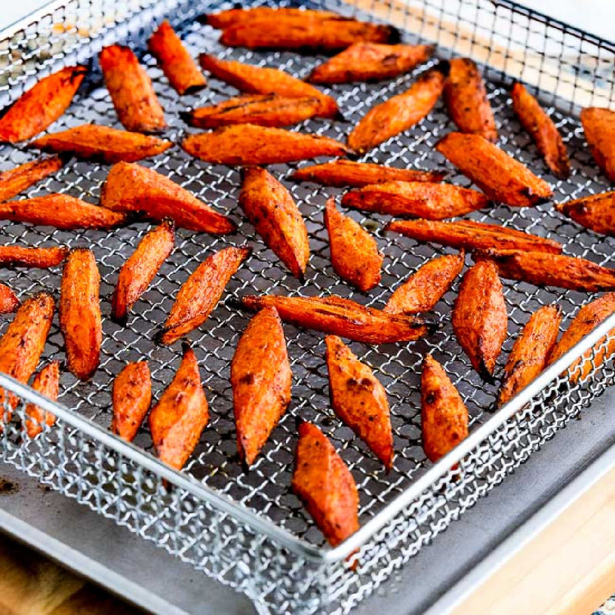 Square image of Air Fryer Carrots shown in basket of Air Fryer.
