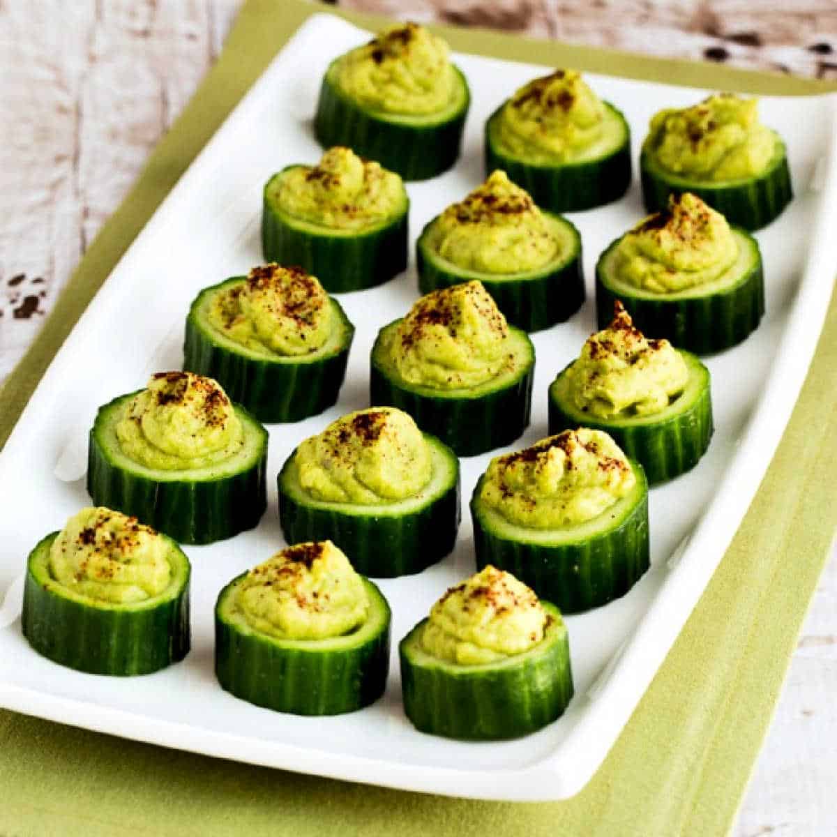 Cucumber Guacamole Appetizer Bites shown on serving platter with green napkin.