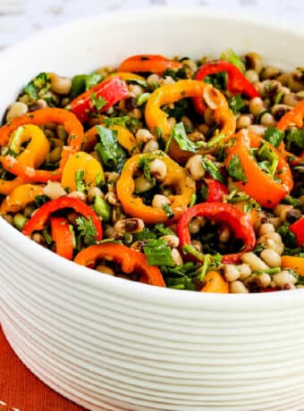 Square image of Black-Eyed Pea Salad with Peppers, Cilantro, and Cumin-Lime Vinaigrette shown in white bowl on napkin.