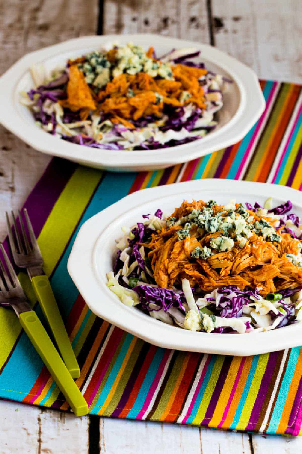 two buffalo chicken bowls on striped napkin with green forks