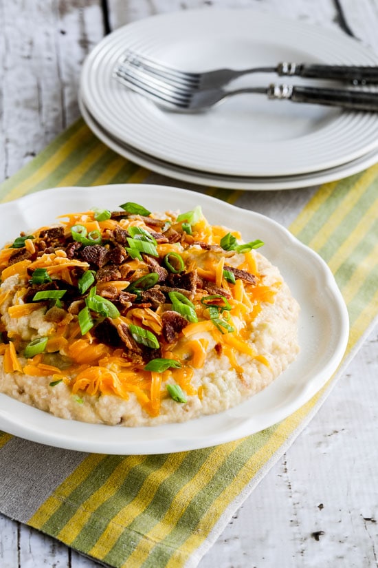 Loaded Cauliflower Mash shown on serving plate with cheese, bacon, and green onions.
