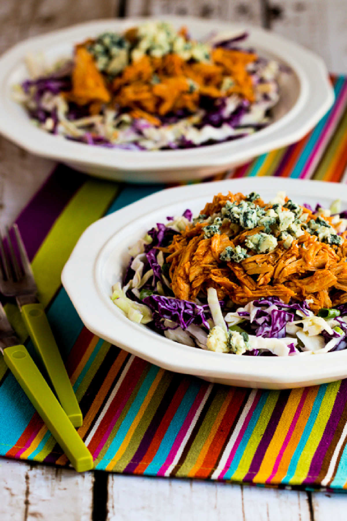 Buffalo Chicken Bowls shown in two serving bowls on vibrant striped napkin napkin