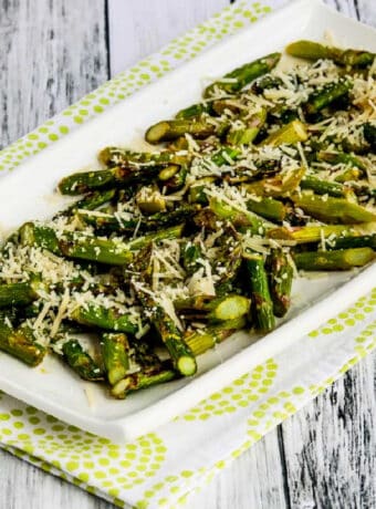 Square image of Air Fryer Asparagus with Lemon and Parmesan on serving platter on green-shite napkin.