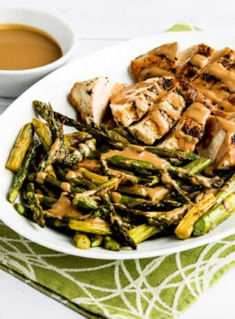 Square image for Chicken and Roasted Asparagus with Tahini Sauce shown on serving platter with sauce in back.