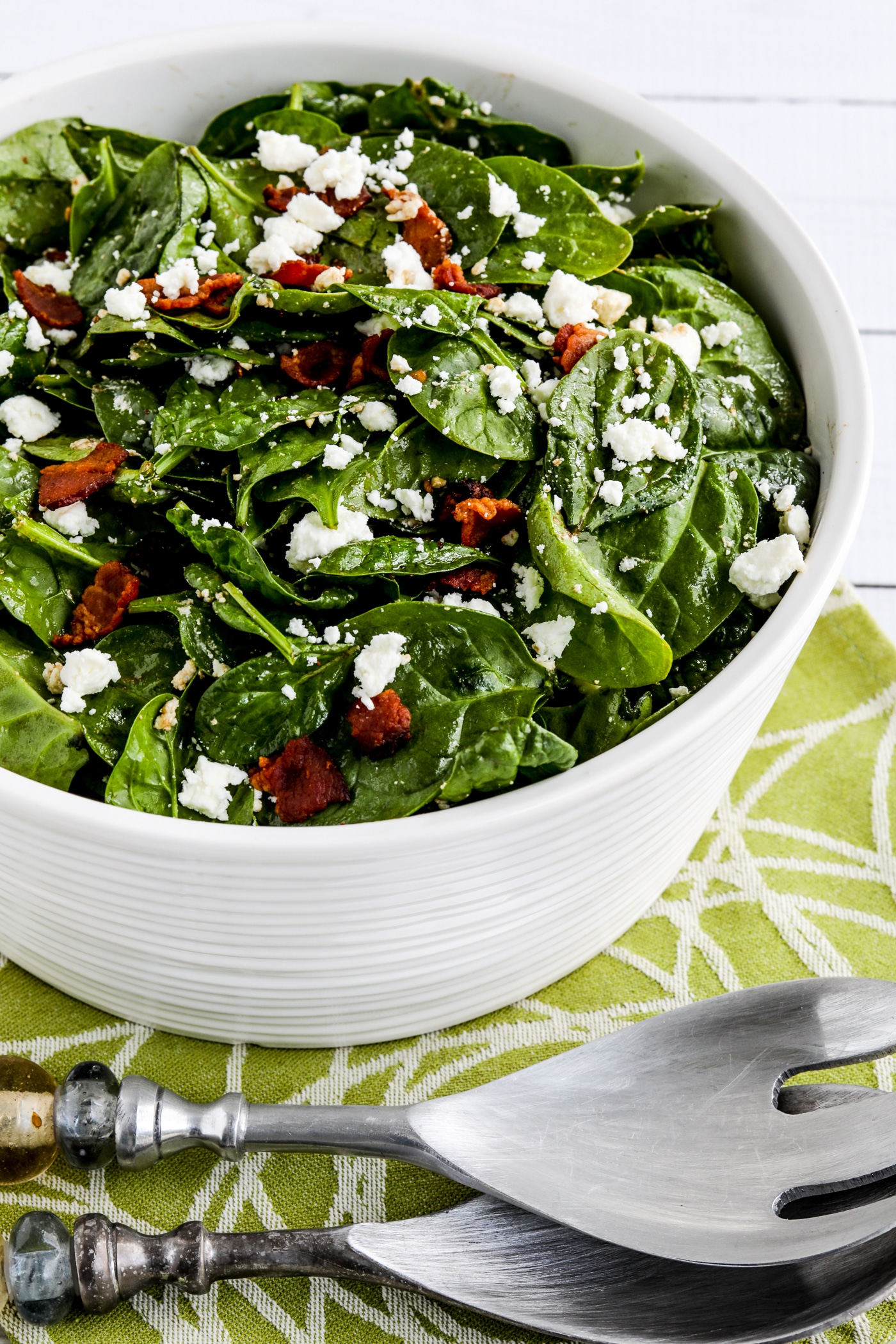 Spinach salad with bacon and feta on a fork serving plate