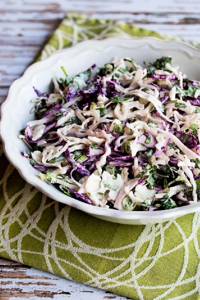 Spicy Mexican Slaw with Lime and Cilantro shown in salad bowl on green-white napkin.