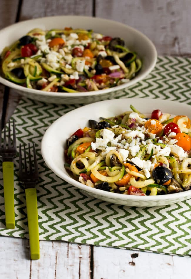 Greek zucchini noodles presented in two bowls with forks