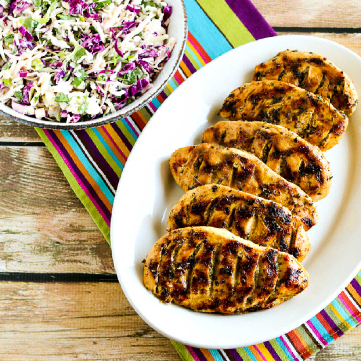 Garlic, Lemon, and Herb Grilled Chicken Breasts shown on serving platter with slaw in background.