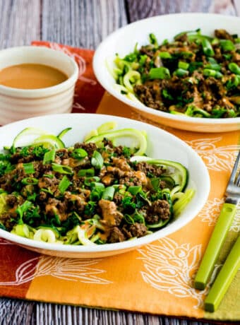 Ground Beef Peanut Sauce Zucchini Noodles in two serving bowls with sauce on the side.