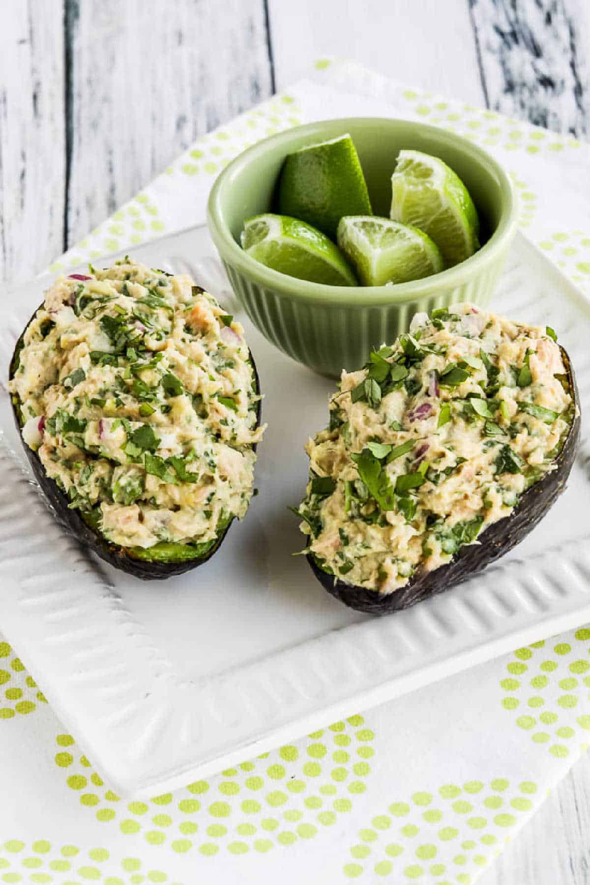 Tuna Stuffed Avocado on serving plate with cut limes