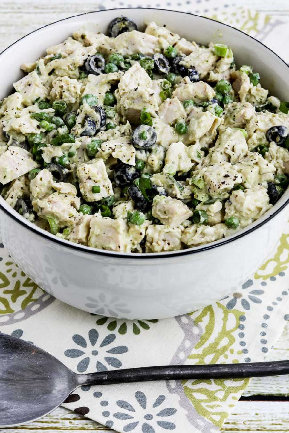 Chicken Pesto Salad in serving bowl with fork shown on patterned napkin