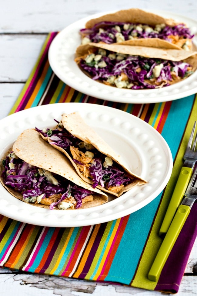Buffalo Chicken Tacos with Blue Cheese Coleslaw on two serving plates with colorful napkin