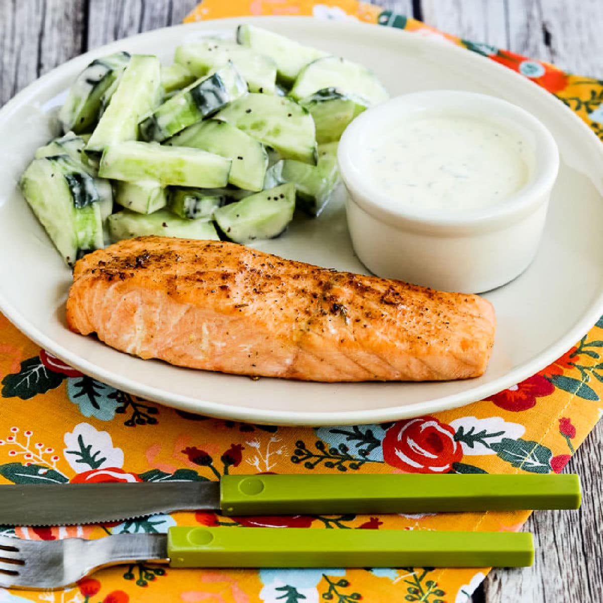 Square image for Air Fryer Salmon Recipe showing cooked salmon on plate with mustard-herb sauce and cucumber salad.