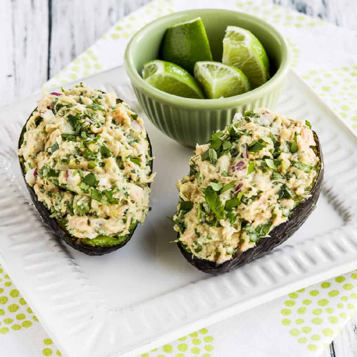 square image of Tuna Stuffed Avocado on serving plate with limes