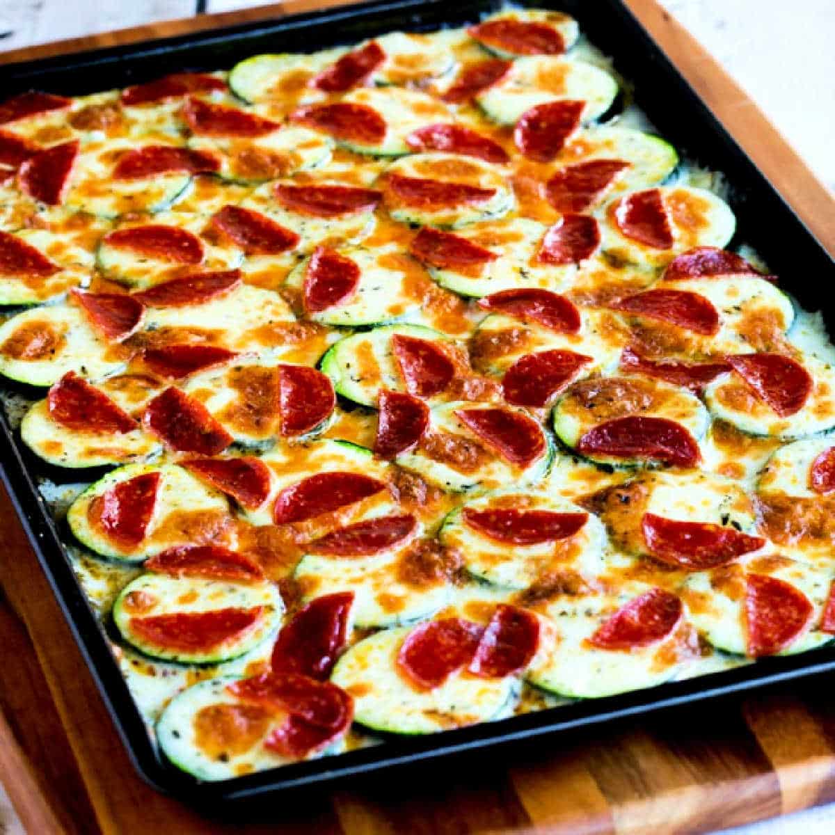 Square image of Broiled Zucchini with Mozzarella and Pepperoni shown on baking sheet.