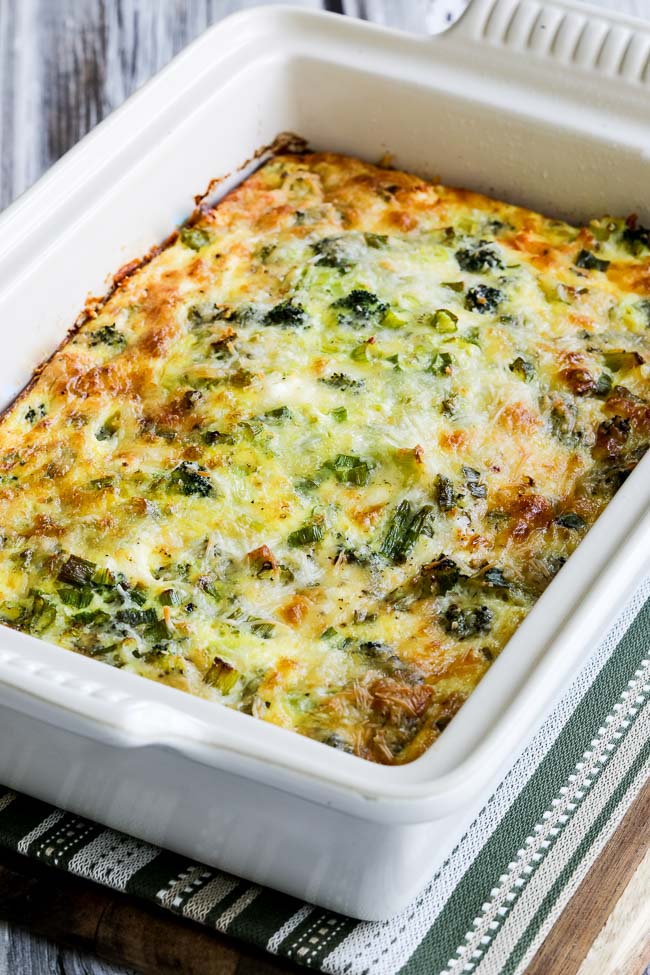 Broccoli and Three Cheese Breakfast Casserole shown in baking dish on striped napkin.