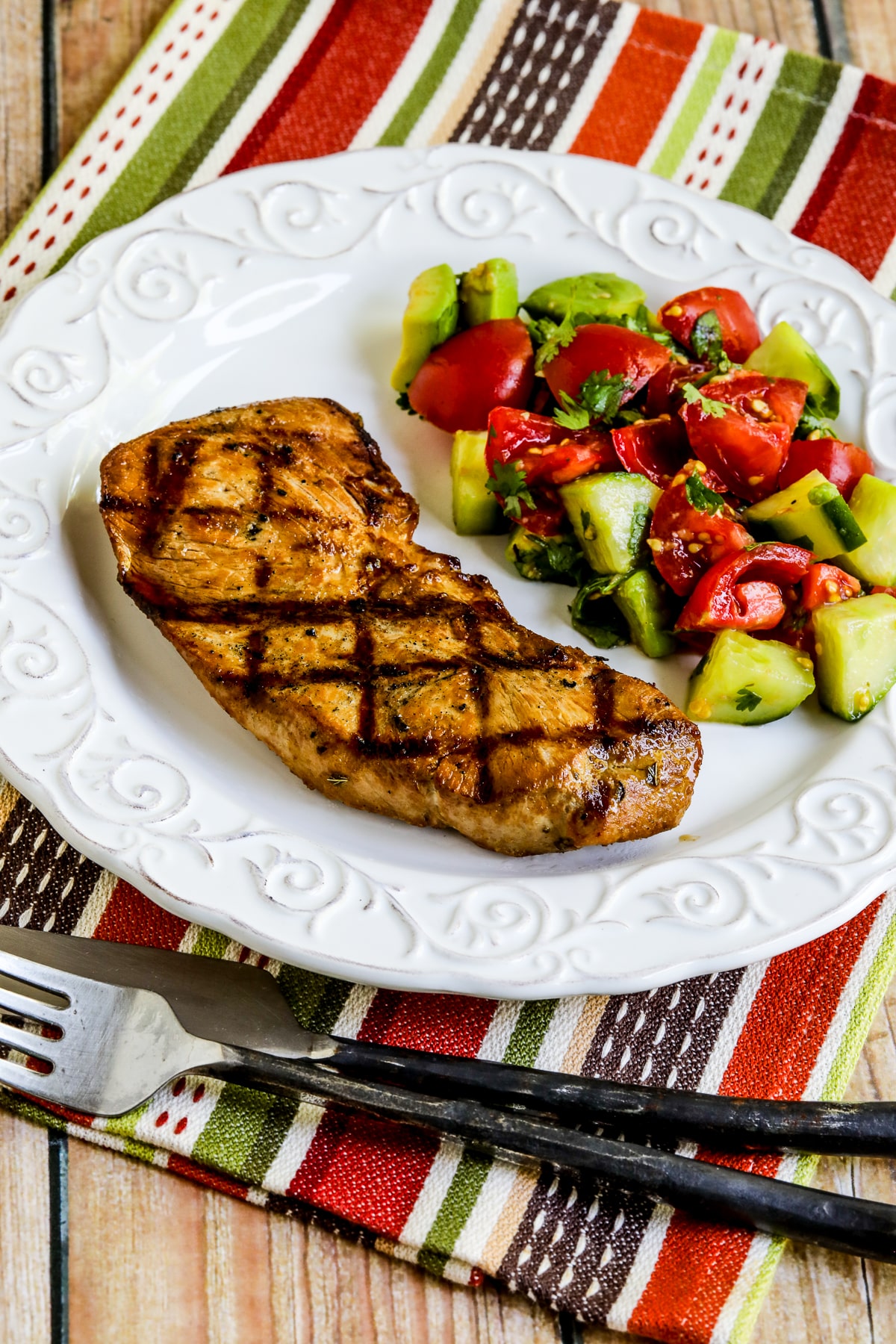 Marinated Grilled Pork Sirloin Chops shown on plate with tomato avocado salad.