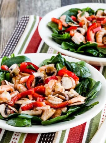 Spinach Salad with Shrimp shown in two serving bowls on colorful napkin.