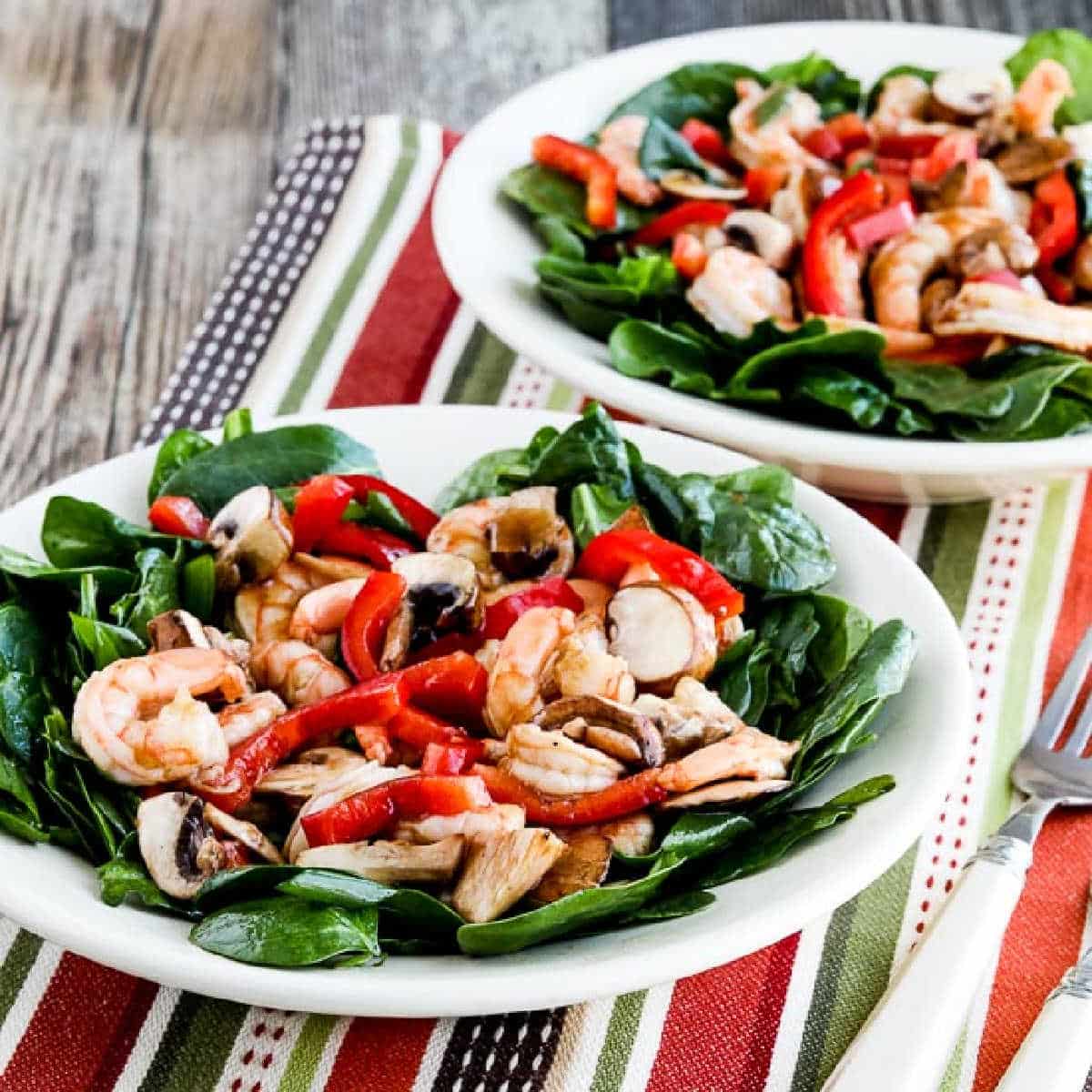 Spinach Salad with Shrimp shown in two serving bowls on colorful napkin.