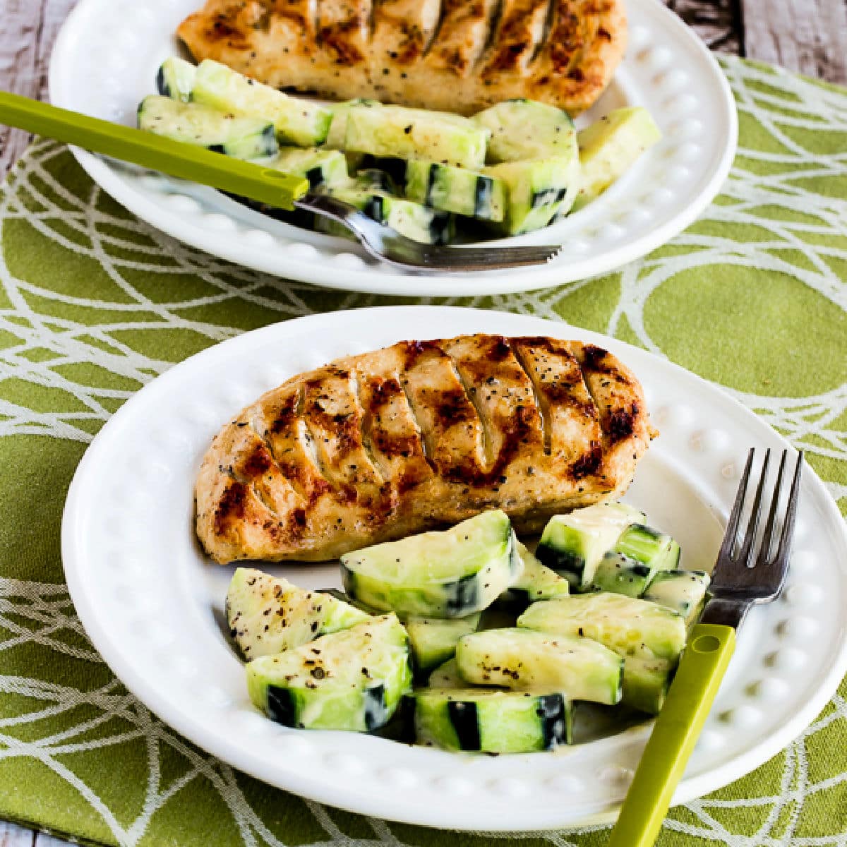 Square image for Completely Foolproof 100% Delicious Grilled Chicken Recipe shown on two serving plates with cucumber salad.