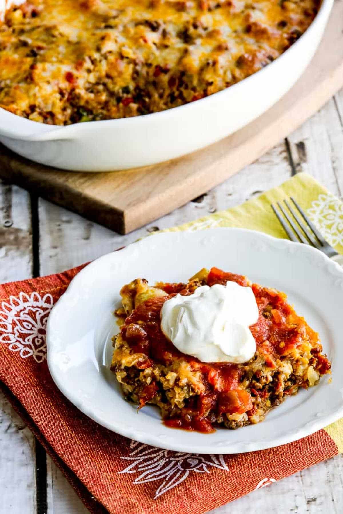 Cheesy Low-Carb Taco Casserole shown in baking dish with one serving on plate